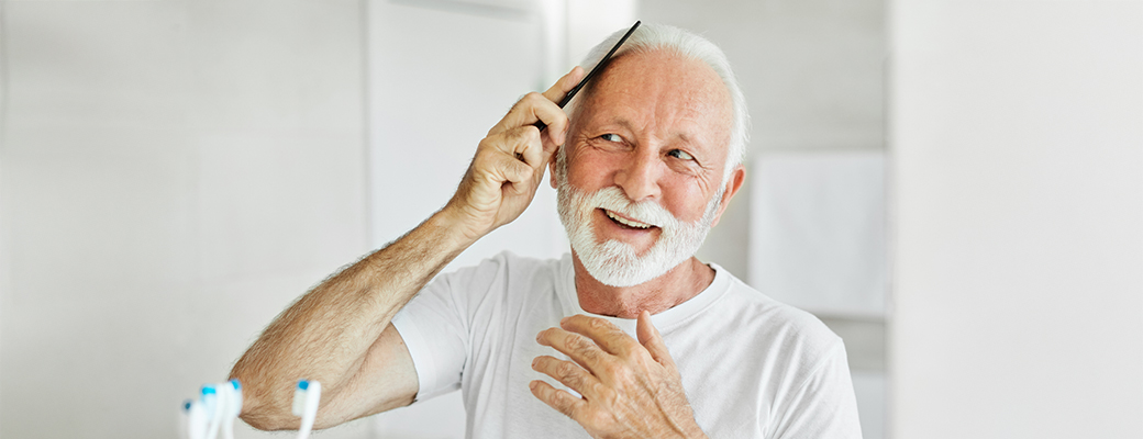 Image of senior man combing his hair while looking in the mirror